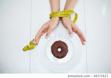 Diet or weight control concept. Centimeter tape and fork on a white background with a place for Diet or weight control concept. Centimeter tape and fork on a white background with a place for 48372625