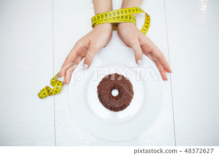 Diet or weight control concept. Centimeter tape and fork on a white background with a place for 48372627