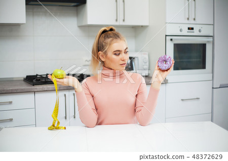 Dieting concept. Young Woman choosing between Fruits and Sweets 48372629
