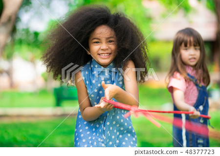 Happy children playing tug of war in the park. Happy children playing tug of war in the park. 48377723