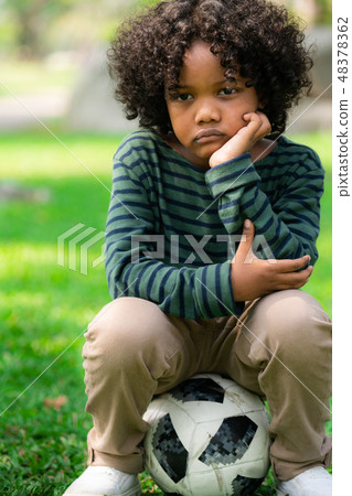 Unhappy little african american kid in the park. Unhappy little african american kid in the park. 48378362