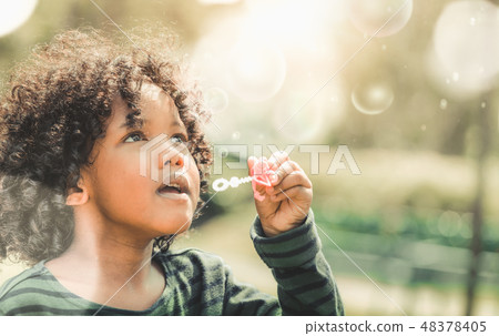 Happy little kid blowing bubble in school garden. 48378405