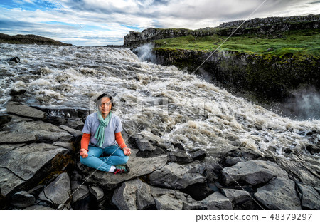 Woman does yoga on Dettifoss Fall in Iceland. Woman does yoga on Dettifoss Fall in Iceland. 48379297