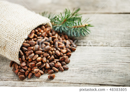 Pine nuts in a bag of burlap on an old vintage Pine nuts in a bag of burlap on an old vintage 48383805