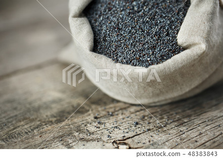 Poppy seeds in a burlap bag on a vintage wooden Poppy seeds in a burlap bag on a vintage wooden 48383843