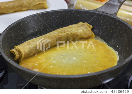 The process of cooking Japanese omelet roll.  48386429