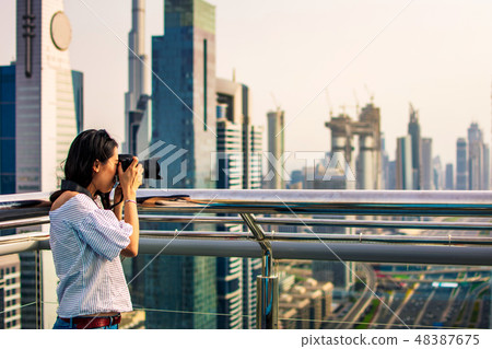 Female tourist taking photo of Dubai cityscape Female tourist taking photo of Dubai cityscape 48387675