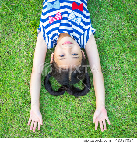 Girl child having fun lying upside down on park 48387854