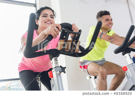 Two friends cycling at gym Two friends cycling at gym 48388920