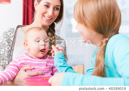 Girl feeding her brother baby with spoon 48389019