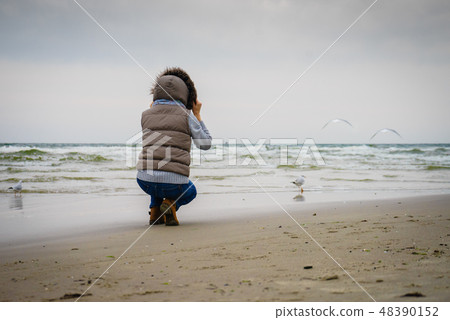Woman walking on beach, autumn cold day Woman walking on beach, autumn cold day 48390152