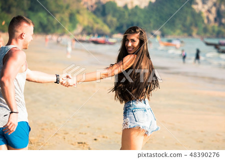 Young happy adult romantic couple running on beach Young happy adult romantic couple running on beach 48390276