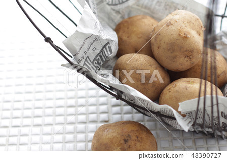  Potato that is wrapped in a newspaper and saved on a white tile 48390727
