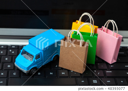 Delivery of orders from the online store. Shopping bags on the laptop keyboard and courier delivery 48393077