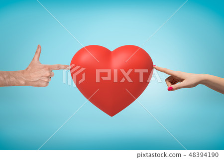 Woman's hand on the right and man's hand doing finger gun on the left touching a big red Valentine Woman's hand on the right and man's hand doing finger gun on the left touching a big red Valentine 48394190