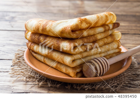 Thin pancakes stacked on a wooden background.  48395450