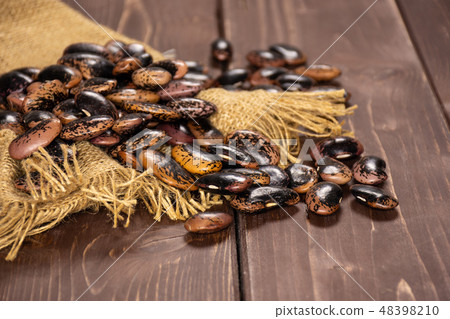 Speckled colored butter beans on brown wood Speckled colored butter beans on brown wood 48398210