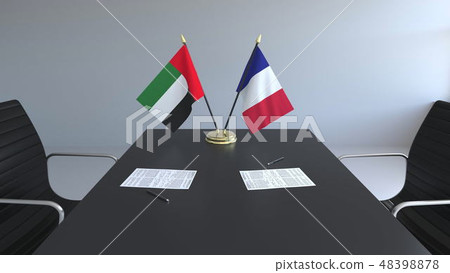 Flags of the United Arab Emirates and France and papers on the table. Negotiations and signing an Flags of the United Arab Emirates and France and papers on the table. Negotiations and signing an 48398878
