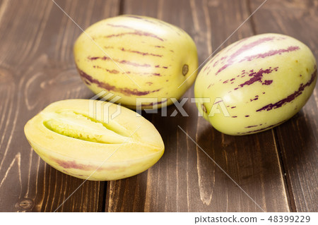 Fresh striped pepino melon on brown wood 48399229