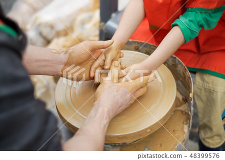 A young child and grandfather grab both hands and make ceramic pottery 48399576