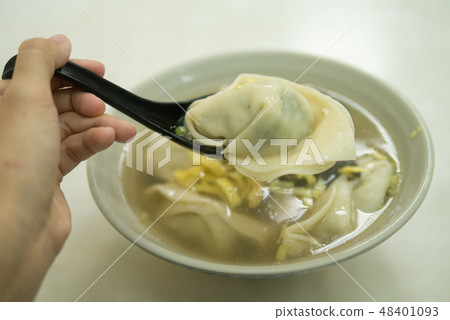 Hand holding spoon with wonton dumpling soup 48401093