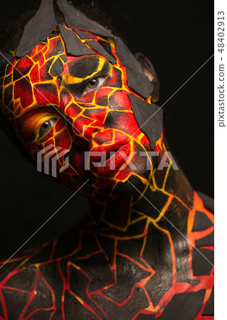 Girl with a painted face on a black background. Body art in the form of a devil 48402913