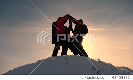 team work and victory. Tourists come to top of snowy hill and rejoice at victory against backdrop of team work and victory. Tourists come to top of snowy hill and rejoice at victory against backdrop of 48403181