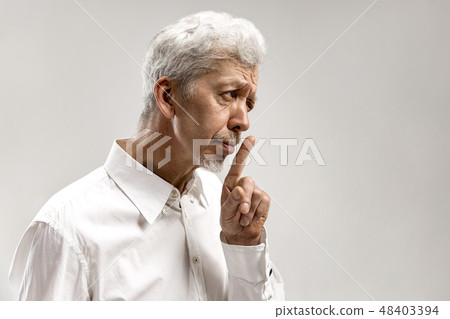 Serious frightened male keeps fore finger on lips Serious frightened male keeps fore finger on lips 48403394