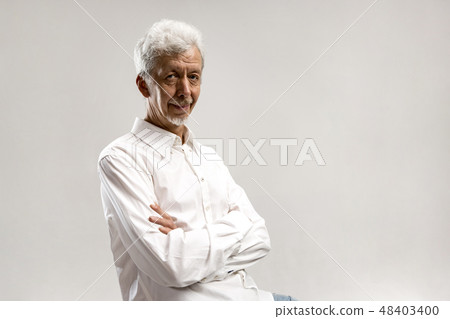 The serious businessman standing and looking at camera against gray background. 48403400