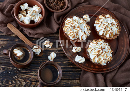 Lemon meringue chocolate tartlets on a table 48404347