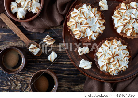 Lemon meringue chocolate tartlets on a table 48404350