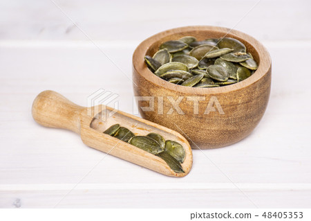 Hulled pumpkin seeds on grey wood Hulled pumpkin seeds on grey wood 48405353