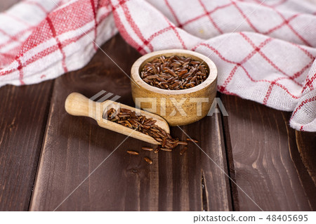 Raw red rice on brown wood 48405695