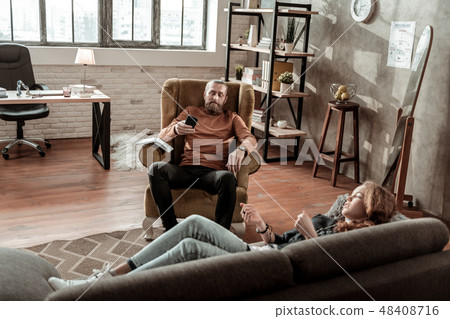 Bearded psychologist using his smartphone during therapy Bearded psychologist using his smartphone during therapy 48408716