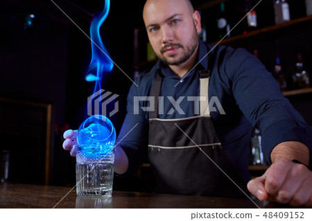 Fiery show at the bar. The bartender makes hot alcoholic cocktail and ignites bar. Bartender Fiery show at the bar. The bartender makes hot alcoholic cocktail and ignites bar. Bartender 48409152