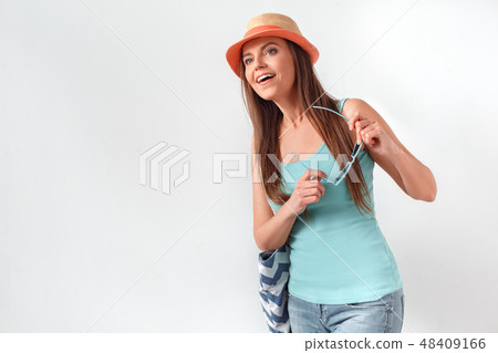 Summer mood. Woman in hat standing studio isolated on white with beach bag holding sunglasses Summer mood. Woman in hat standing studio isolated on white with beach bag holding sunglasses 48409166