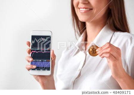 Cryptocurrency. Woman standing isolated on white showing screen of smartphone with statistics Cryptocurrency. Woman standing isolated on white showing screen of smartphone with statistics 48409171