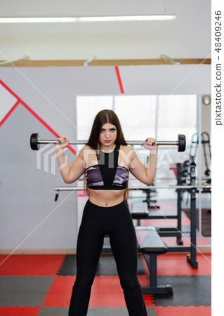 Beautiful girl crouches with a barbell on the Beautiful girl crouches with a barbell on the 48409246
