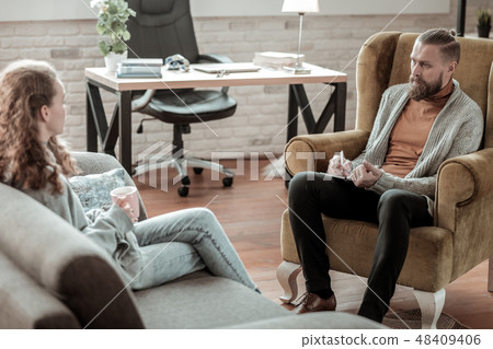 Curly teenager drinking tea and talking to her professional counselor 48409406