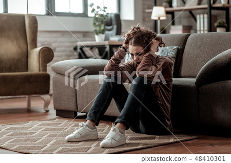 Curly teenage girl wearing white sneakers feeling lonely and isolated Curly teenage girl wearing white sneakers feeling lonely and isolated 48410301