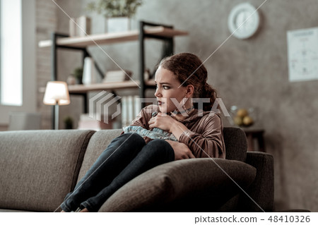 Teenage girl feeling lonely and unhappy sitting on sofa at home 48410326