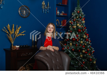 Very beautiful woman stands near the fireplace in 48410366