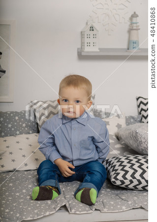 A little boy sits in on pillows in clothes. A little boy sits in on pillows in clothes. 48410868