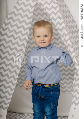 A little boy is standing in a tepee and smiling. A little boy is standing in a tepee and smiling. 48410878