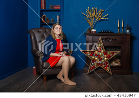 Very beautiful woman stands near the fireplace in Very beautiful woman stands near the fireplace in 48410947