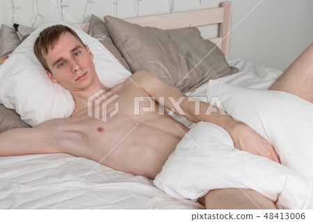 Handsome young adult man sleeping in bed 48413006