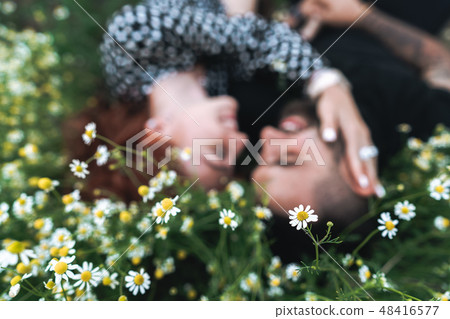 Young couple lies on the field with daisies. Young couple lies on the field with daisies. 48416577