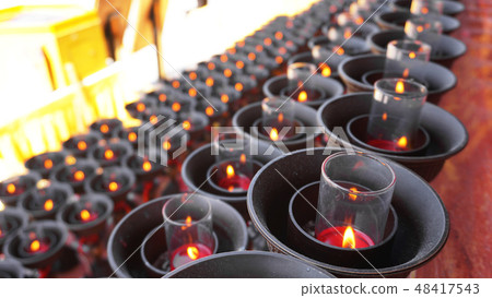 Burning big red candles in Buddhist temple 48417543