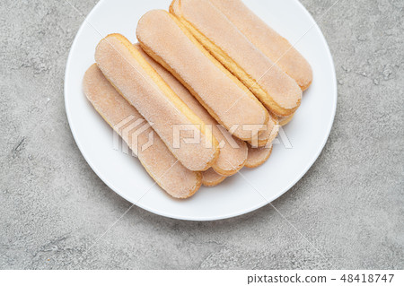 Italian Savoiardi ladyfingers Biscuits in plate on concrete backgound Italian Savoiardi ladyfingers Biscuits in plate on concrete backgound 48418747