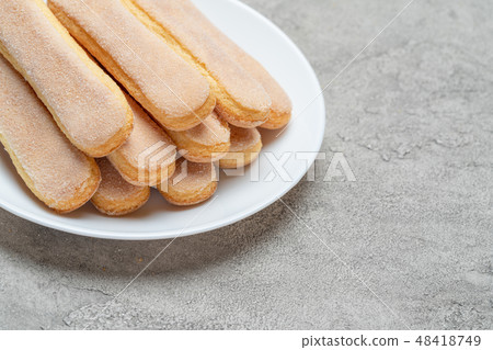 Italian Savoiardi ladyfingers Biscuits in plate on concrete backgound Italian Savoiardi ladyfingers Biscuits in plate on concrete backgound 48418749